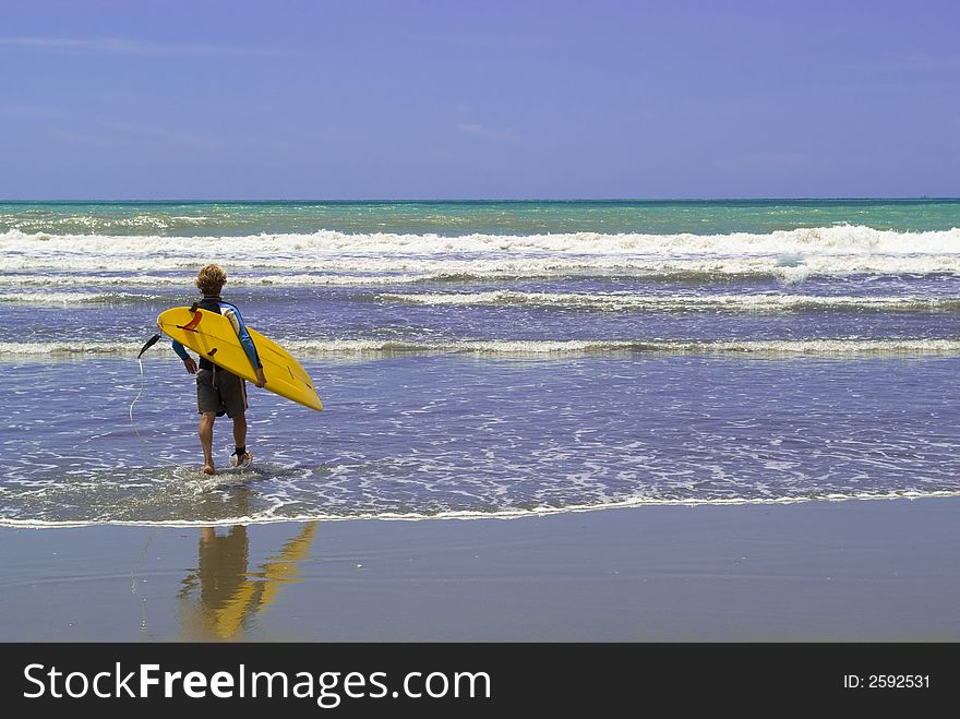 A surfer enter into the rough sea, ready to surf. A surfer enter into the rough sea, ready to surf.