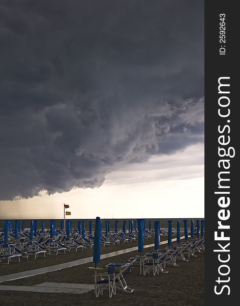 Menacing clouds over a beach with umbrella and seats, Italy. Menacing clouds over a beach with umbrella and seats, Italy