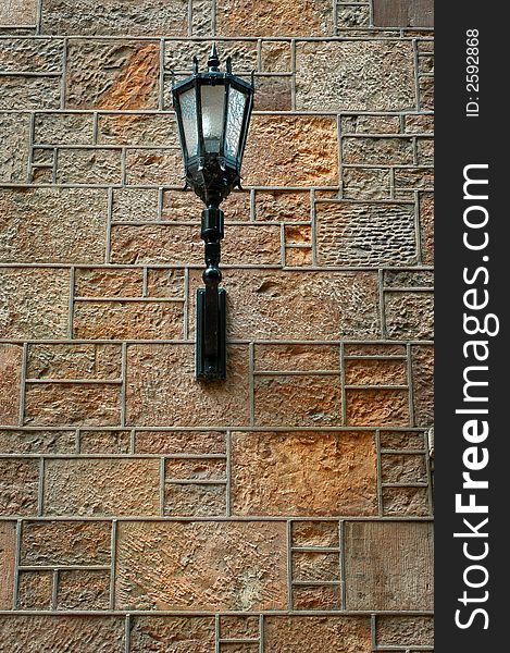 Detailed ornate black iron light fixture mounted on stone wall