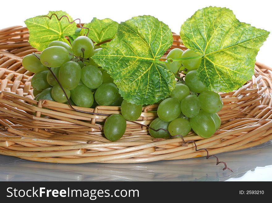 Green grape cluster with leaves on a basket