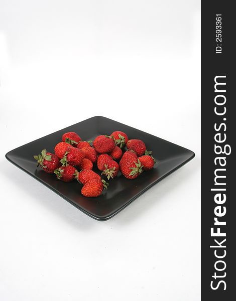 Strawberries on Black Plate over White with knife