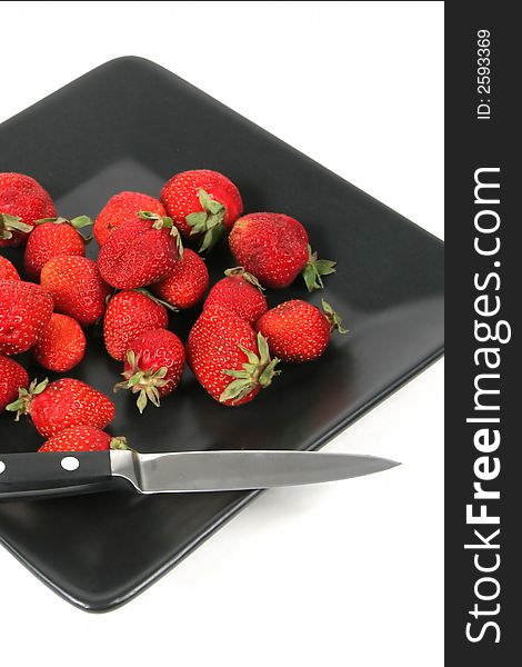 Strawberries on Black Plate over White with knife