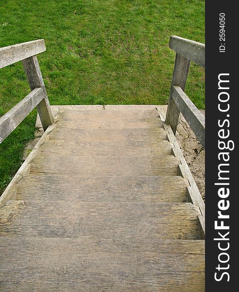 Old well worn wooden outdoor staircase with the emphasis on going downwards towards grass. Old well worn wooden outdoor staircase with the emphasis on going downwards towards grass.