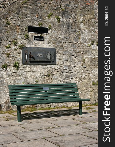 Green bench in a courtyard situated beneath an old cast iron antique bread oven. Green bench in a courtyard situated beneath an old cast iron antique bread oven.