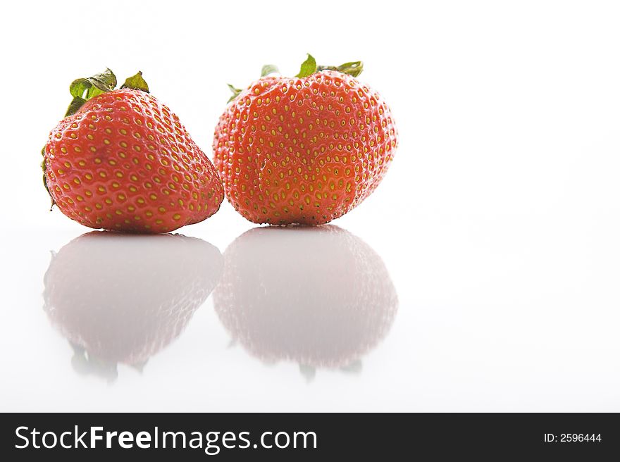 Two strawberries on a white background with reflection