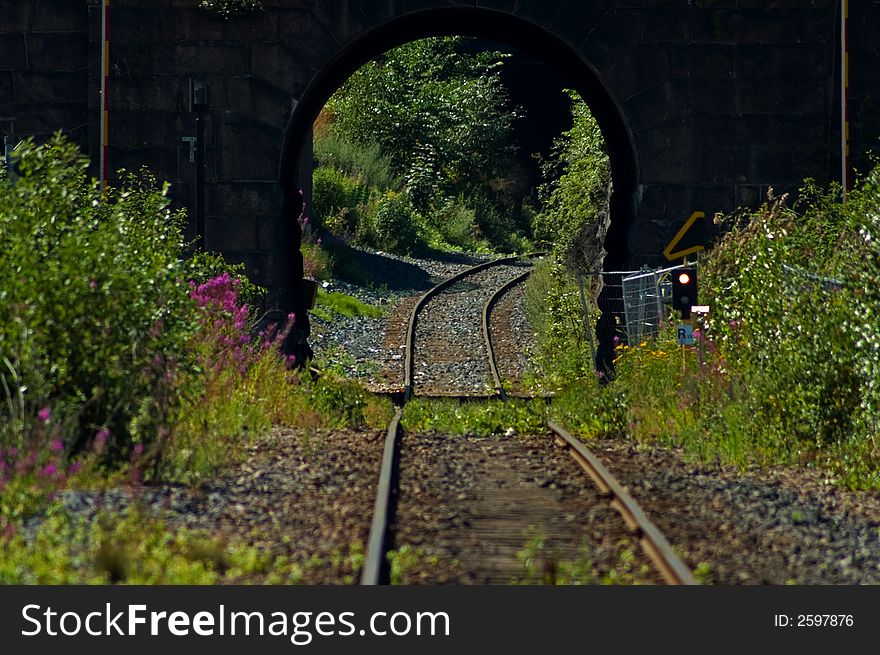 Train tracks going under a stone bridge