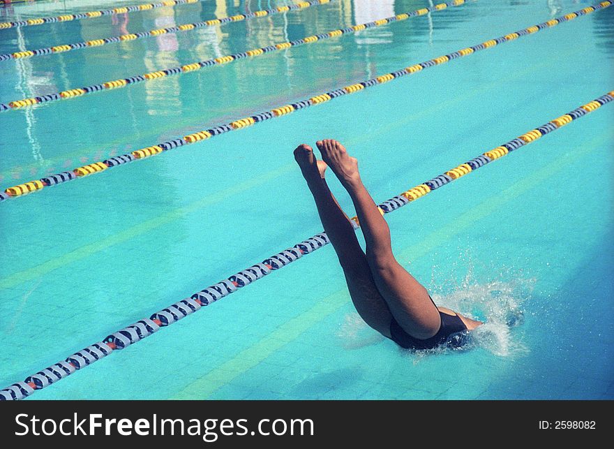 A young girl diving into the pool at a local state swimming championship. A young girl diving into the pool at a local state swimming championship