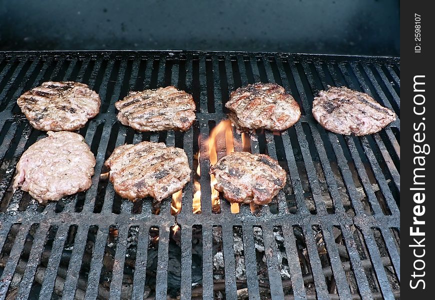 Photo of a burgers being cooked on a smoker grill. Photo of a burgers being cooked on a smoker grill