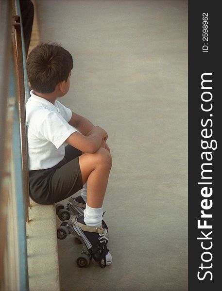 A young boy wearing skates, waiting his turn at the rink. A young boy wearing skates, waiting his turn at the rink.