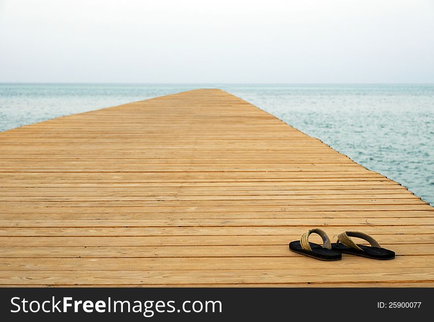 Thongs on pier with sea at background