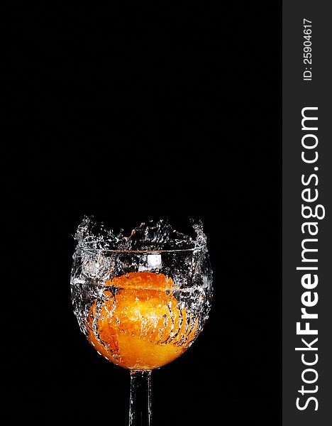 Peach plunged in a glass of water in a black background