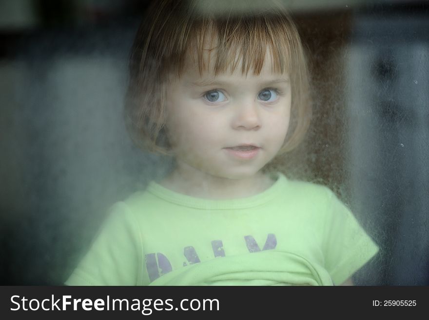 Little girl looking out the scratched glass. Little girl looking out the scratched glass