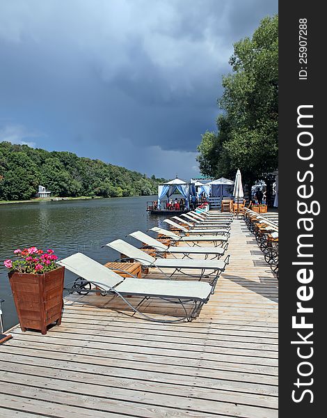 A Lounge chairs on a wooden pier. Moscow river