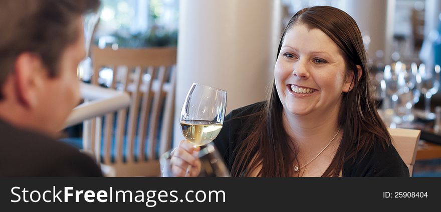 Couple in restaurant drinking wine and smiling. Focus on woman