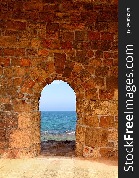 View on the dark blue sea through a window in an old fortification. View on the dark blue sea through a window in an old fortification