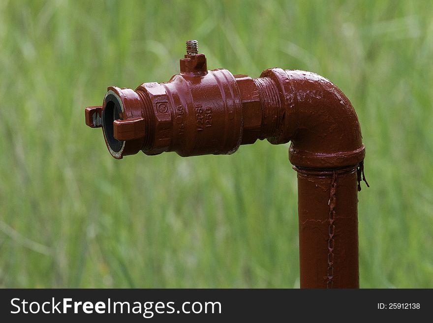 A red water tap in a field