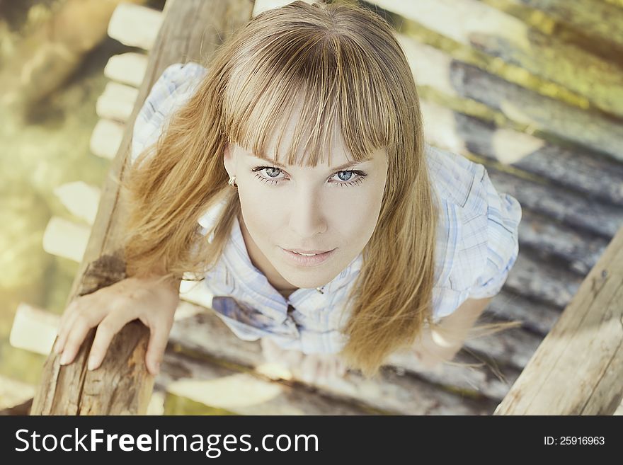 Fashion photo of young beautiful woman stending on a bridge and looking up at camera