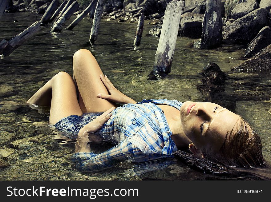 Fashion photo of young beautiful woman lying in water with eyes closed