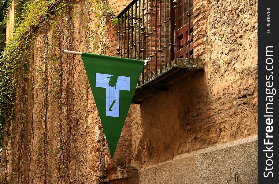 The symbol of the Spanish puppeteers hanging from the balcony of a villa. The green flag depicting a white t shape and a hand with strings marks the location of puppeteers' schools in towns. The symbol of the Spanish puppeteers hanging from the balcony of a villa. The green flag depicting a white t shape and a hand with strings marks the location of puppeteers' schools in towns.