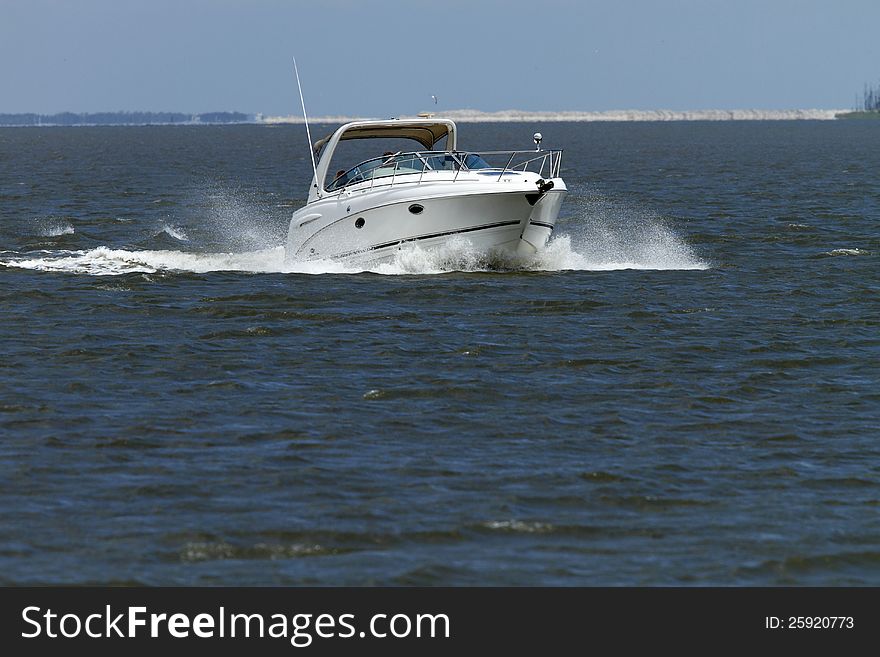 A power boat cruising into the wind with spay flying from the bow. A power boat cruising into the wind with spay flying from the bow