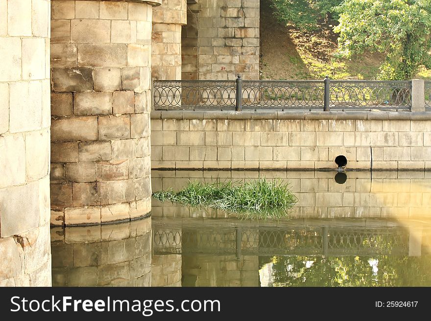 Empty embankment of the city river under a stone bridge. Empty embankment of the city river under a stone bridge