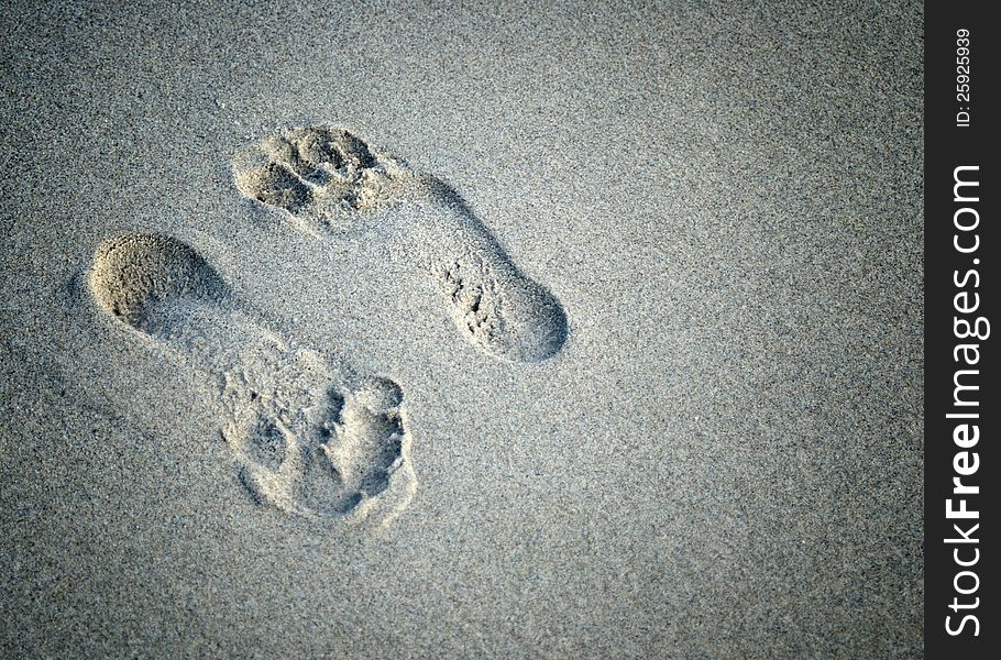 A pair of foot prints left in sand