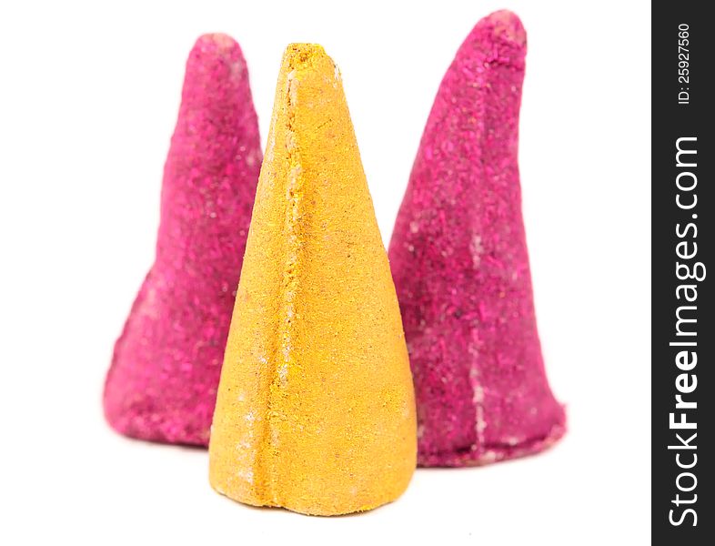 Pink and yellow incense cones close-up on a white background