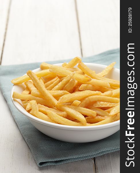 Bowl of french fries on white wooden surface. Bowl of french fries on white wooden surface