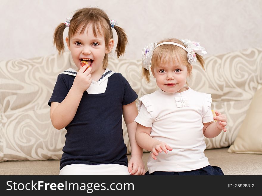 Two little girls eat candies