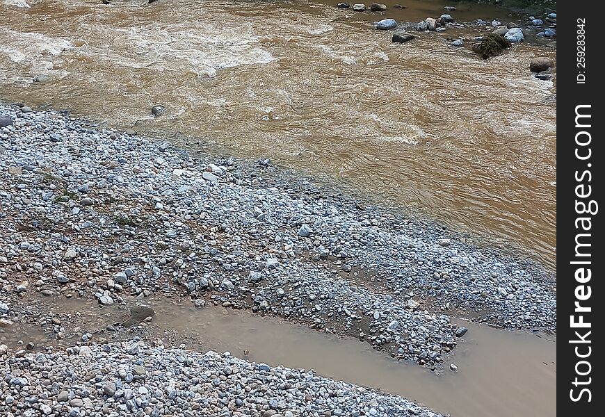 A Muddy Stream Gushing Past A Rocky Terrain