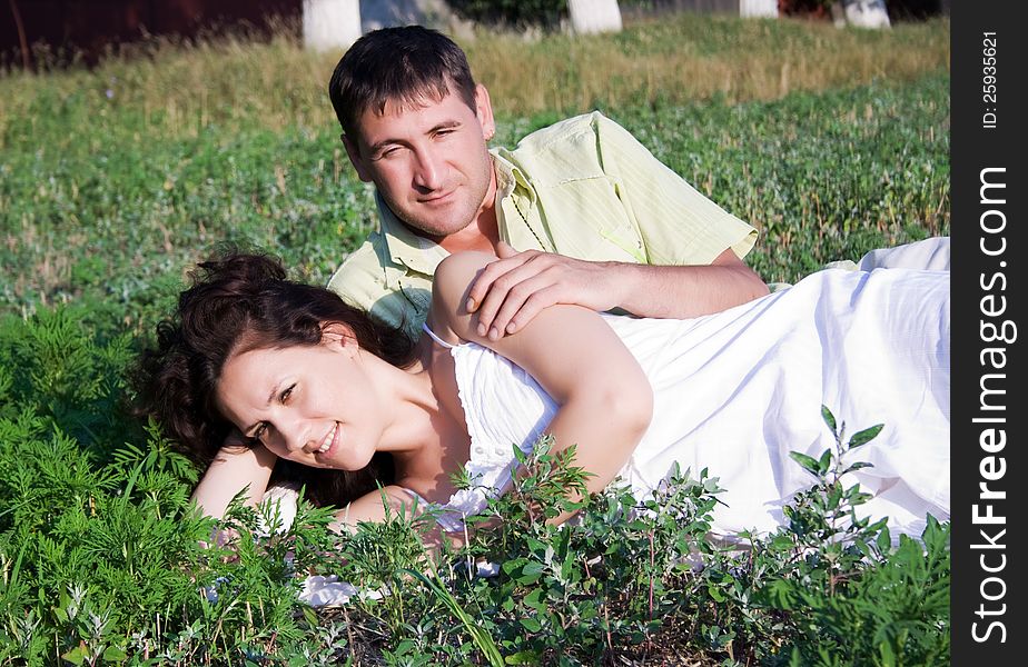 Portrait of a pretty young women lying on grass with her boyfriend in the park - Outdoor. Portrait of a pretty young women lying on grass with her boyfriend in the park - Outdoor