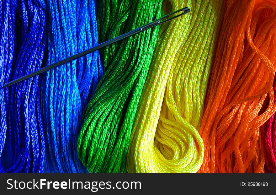 Vertical color photo of a rainbow of threads with a needle. Vertical color photo of a rainbow of threads with a needle.