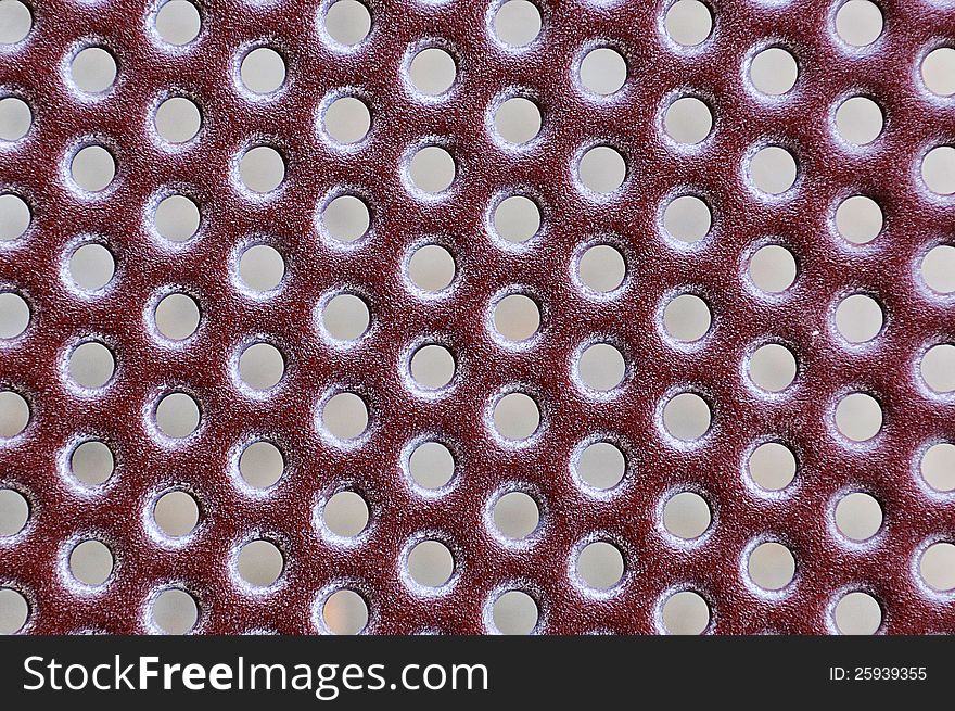 Red metal grate with a repeating hole patern for use as a background. Red metal grate with a repeating hole patern for use as a background
