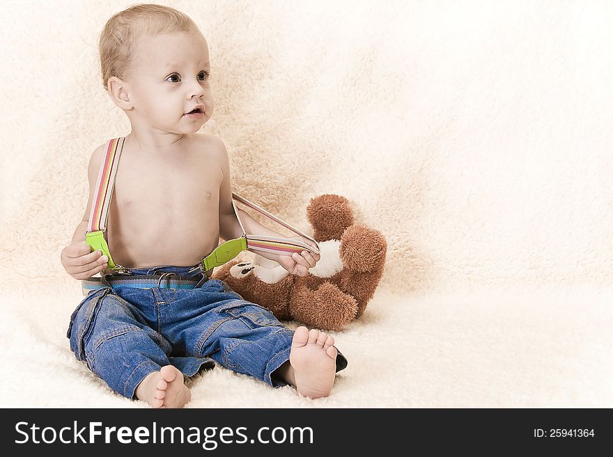 The child sits on a floor with a toy in jeans and barefoot. The child sits on a floor with a toy in jeans and barefoot