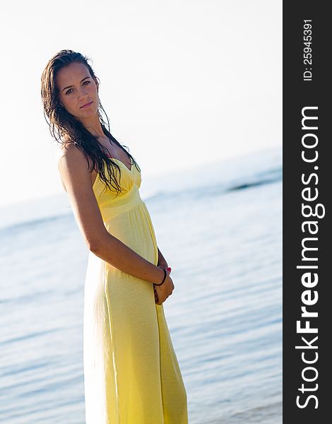 Brunette in flowing yellow dress with background seafront on sunny Spanish beach. Brunette in flowing yellow dress with background seafront on sunny Spanish beach