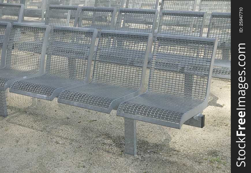 A row of empty, metal seats. A row of empty, metal seats.