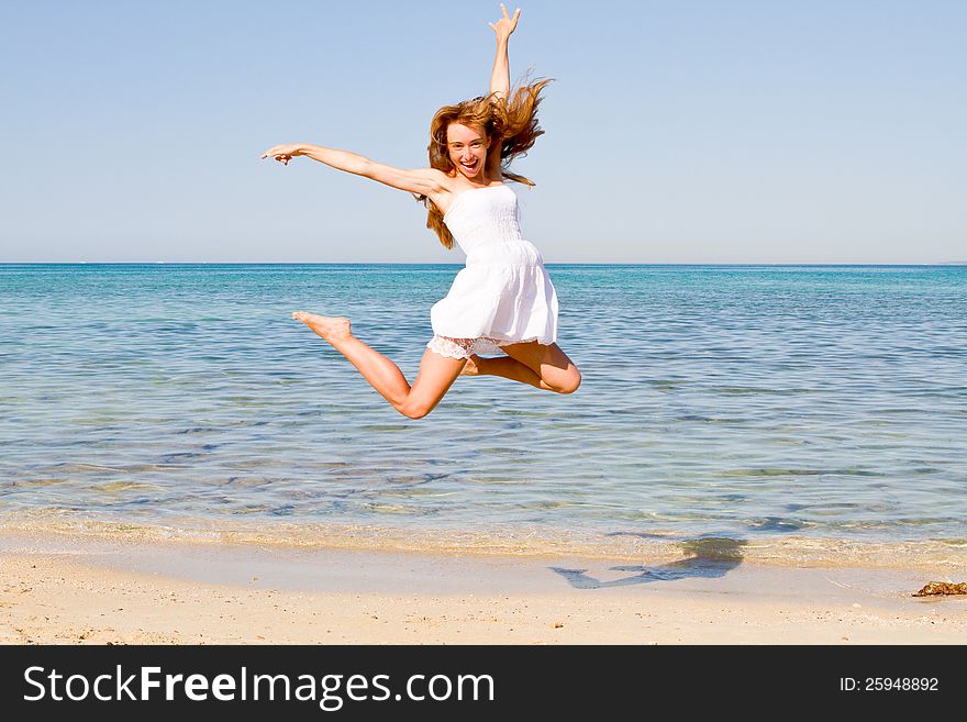 Happy Young Woman Jumping On The Beach