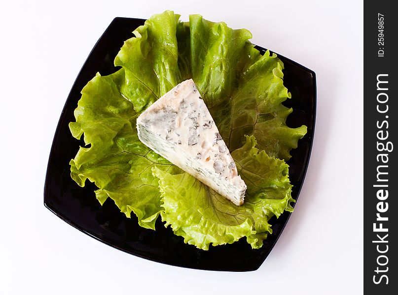 Piece of cheese with leaves on plate isolated on white. Piece of cheese with leaves on plate isolated on white