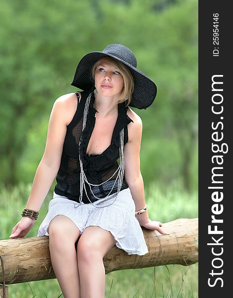 Girl in hat sitting on a log. Girl in hat sitting on a log