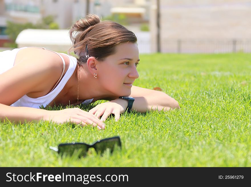 Portrait of a pretty girl lying on the grass in the summer