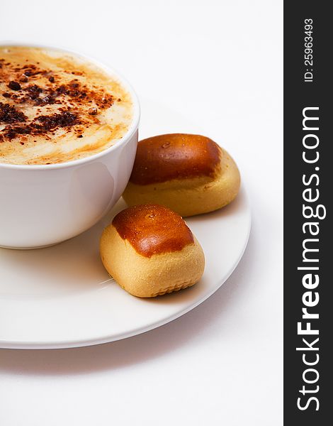 A cup of coffee and sweets on a plate closeup,  on a white background. A cup of coffee and sweets on a plate closeup,  on a white background.