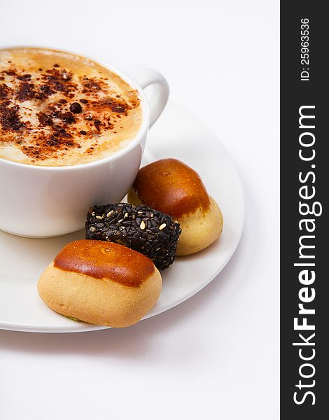 A cup of coffee and sweets on a plate closeup, on a white background. A cup of coffee and sweets on a plate closeup, on a white background.