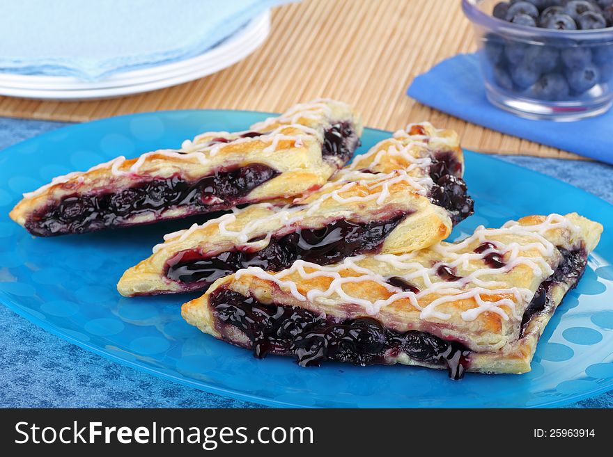 Three blueberry turnovers on a blue platter