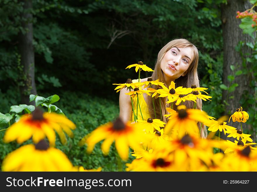 Close-up portrait of a young woman with yellow flowers against a background of trees. Close-up portrait of a young woman with yellow flowers against a background of trees