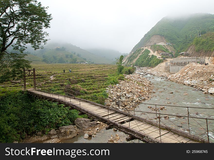 Cloudy landscape with rice terraces and old bridge over river in Sapa, Vietnam. Cloudy landscape with rice terraces and old bridge over river in Sapa, Vietnam.