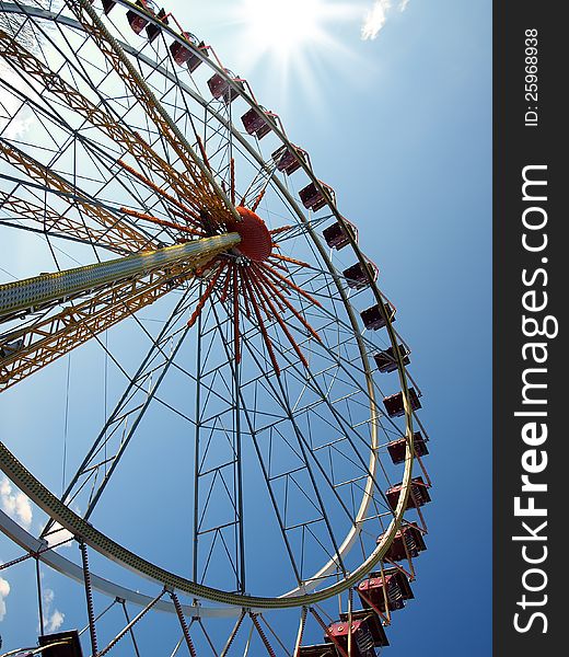 Ferris wheel in the background of blue sky and sun