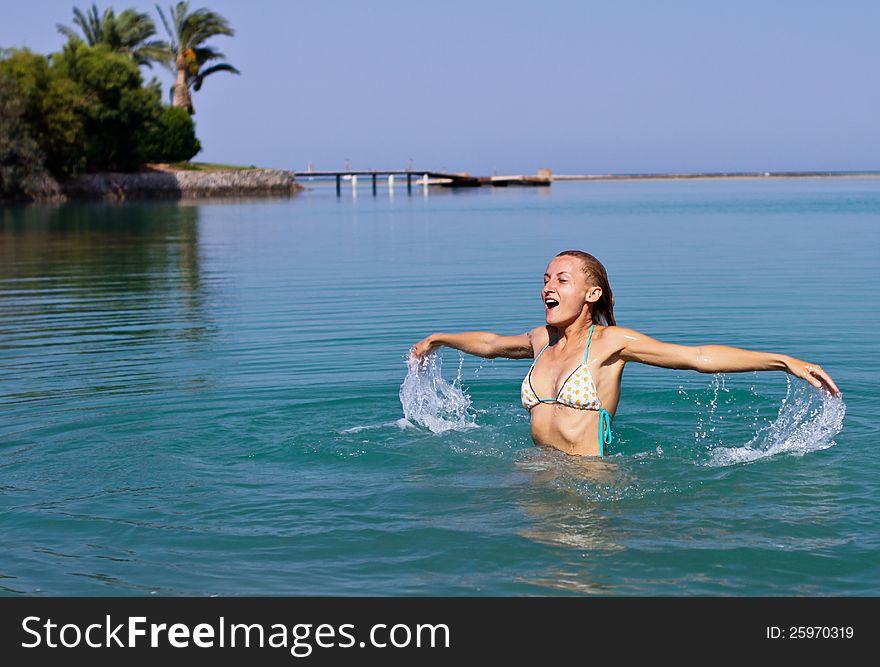 Happy young woman playing in the sea