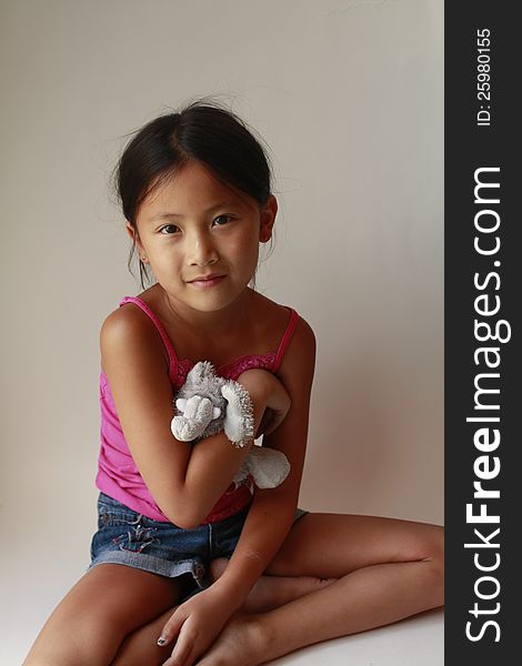 Little Chinese girl with stuffed elephant sitting down. Little Chinese girl with stuffed elephant sitting down