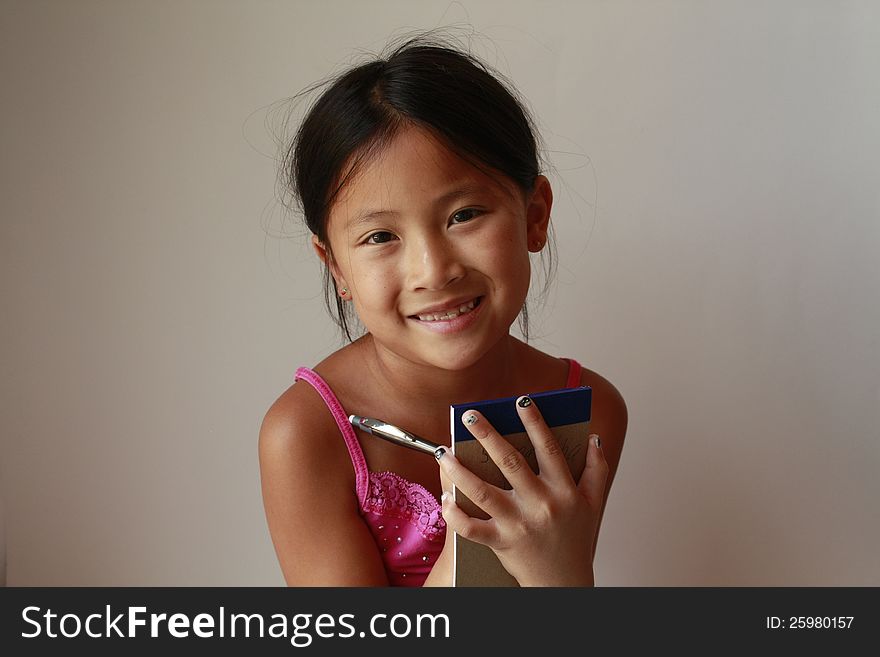 Little Chinese girl holding writing pad and pen. Little Chinese girl holding writing pad and pen