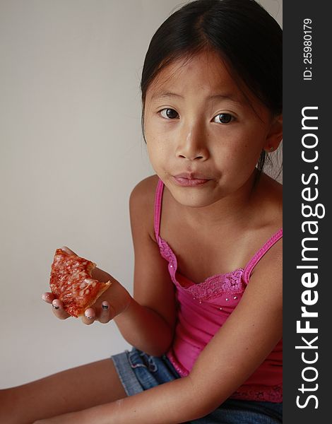 Little Chinese Asian girl eating a slice of pizza. Little Chinese Asian girl eating a slice of pizza